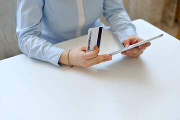 girl in a soft blue shirt sitting at a white table is doing online shopping. shop online home concept. Girl chooses gifts online.