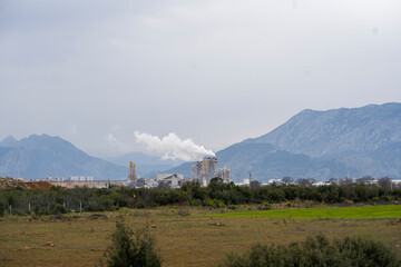 Industrial Pipes with smoke in industrail zone at mountain background. It is air pollution due to smoke. 