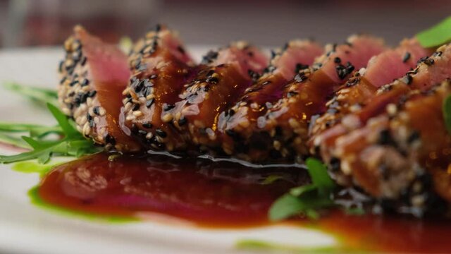 A close-up look of freshly made Sesame Crusted Tuna, Seared Tuna in 4K. Concept of cooked tuna with vegetables and sesame seeds nicely decorated by the chef in a serving plate on the table.