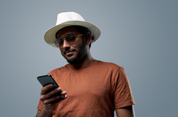 Smartphone and messaging. Portrait of a hindu guy dressed in stylish clothing which uses his mobilephone.