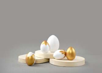 Mock up Easter composition with golden painted eggs and round podiums on grey background. Minimalist luxury concept for greeting card or sale. Creative eco design.
