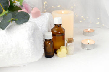 Fototapeta na wymiar Aromatherapy concept with essential oil bottle, sea salt, burning candles and towel. Spa or herbal medicine still life composition. Copyspace.