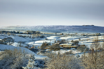 Fototapeta na wymiar Farmland and homes and a snowy view in the Yorkshire Dales at 900ft