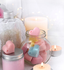 Obraz na płótnie Canvas Spa aromatherapy composition with bath cosmetics on light background. Body care cream, heart shape soap and burning candles. Romantic concept for Mothers day, Valentines day or wedding.