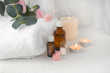 Aromatherapy concept with essential oil bottle, sea salt, burning candles and towel. Spa or herbal medicine still life composition. Copyspace.