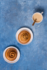 Freshly baked cinnamon bun stuffed with spices and cocoa on a blue background. Sweet homemade cakes.
