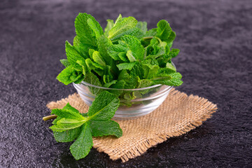 Fresh mint in a glass bowl on a black background.