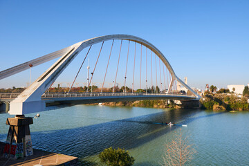 Rowboats in the Guadalquivir river and La Barqueta bridge, Seville, Spain