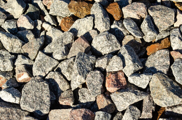 Background of natural grey granite crushed stone, macadam. Macro photo of texture of broken stone or rubble with place for text. Crushed rock. Construction Materials. Textures.