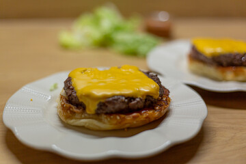 Process of cooking self made burgers at home. Cheesy burger on a white plate