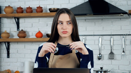 Close up thoughtful woman housewife in apron thinks solution problem holiday food menu in home kitchen. Female chef cook study online remote video call conference laptop, distance education course
