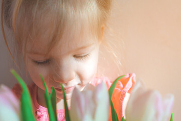 little girl in a pink dress with a bouquet of flowers. child holding a bouquet of tulips