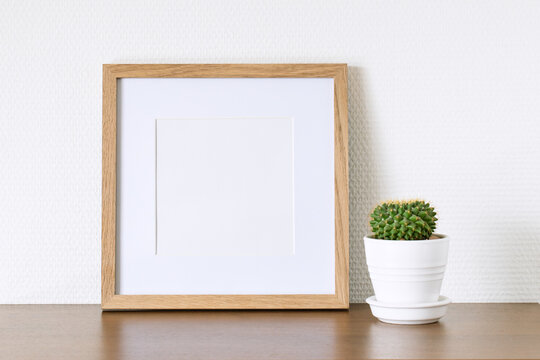 Square wooden photo frame and cactus on the table.