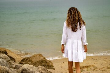 Person in white  summer dress walking on the beach in Poole