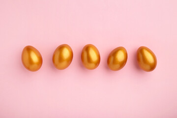 Gold eggs on the pink pastel background. Easter concept.