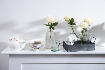 Bouquet of white roses in a glass figured vase on a white fireplace console.