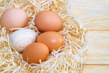 Eggs and wooden egg in a nest with wood shavings. Idea for celebrating Easter