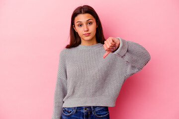 Young Indian woman isolated on pink background showing a dislike gesture, thumbs down. Disagreement...