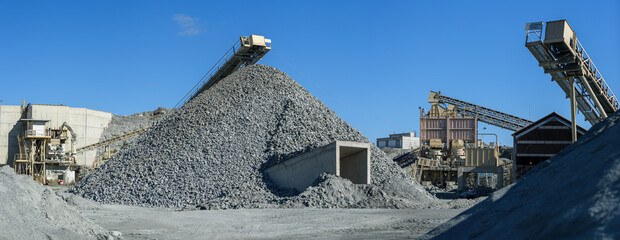 Panorama of stone crushing and screening plant with piles of gravel and machinery