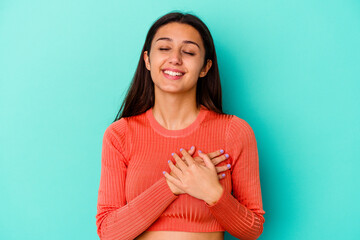 Obraz premium Young Indian woman isolated on blue background laughing keeping hands on heart, concept of happiness.