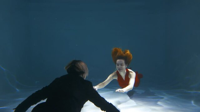 A guy and a girl swim towards each other under water