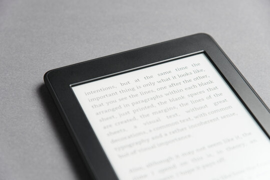 Closeup image of an electronic reader with text on the screen on a grey surface