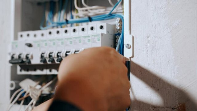 An electrician assembles an electrical panel in an apartment.
