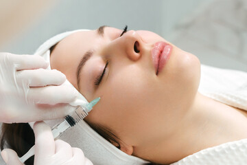 The doctor cosmetologist makes the rejuvenating facial injections procedure for tightening and...