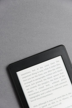 Closeup image of an electronic reader with text on the screen on a grey surface