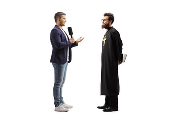 Full length profile shot of a reporter with a microphone talking to a catholic priest