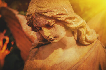 Antique statue of gold and sad angel in the sunlight. Close up. Selective focus on eyes.