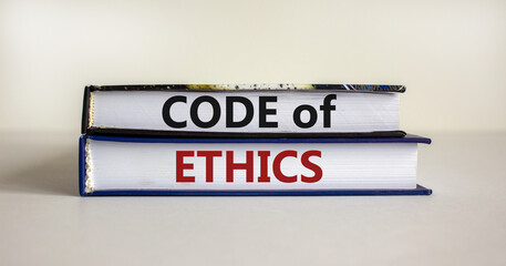 Code of ethics symbol. Concept words 'Code of ethics' on books on a beautiful white table, white background. Business and code of ethics concept. Copy space.