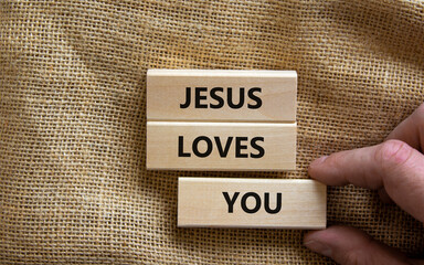 Jesus loves you symbol. Concept words 'Jesus loves you' on wooden blocks on a beautiful canvas background, prayer hand. Copy space. Religion and Jesus loves you concept.