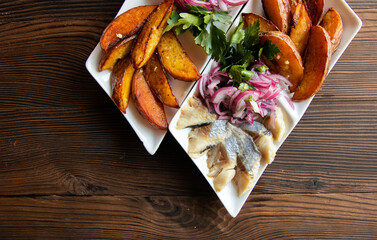 Fried potatoes, pickled herring, with onions on a beautiful background