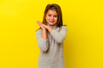Little caucasian girl isolated on yellow background feeling energetic and comfortable, rubbing...