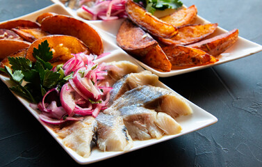 Fried potatoes, pickled herring, with onions on a beautiful background
