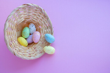 An overturned basket in the shape of a hat with eggs on a pink background. Easter Concept