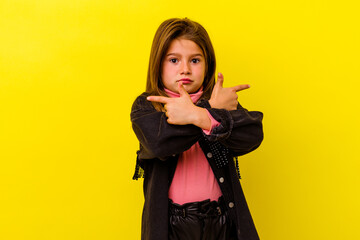 Little caucasian girl isolated on yellow background points sideways, is trying to choose between two options.