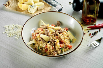 Classic Italian risotto with parmesan cheese, creamy sauce, beef and vegetables, served in a white bowl on a wooden background. Restaurant food