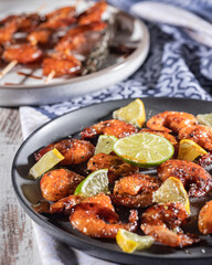 A black plate with homemade fried shrimp skewers with garlic, lemon and herbs, grilled shrimps dish, selective focus