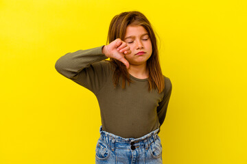 Little caucasian girl isolated on yellow background showing a dislike gesture, thumbs down....