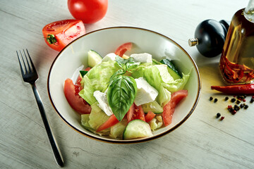 Diet and delicious vegetable salad with feta cheese, served in a blue bowl on a wooden background. Healthy food.