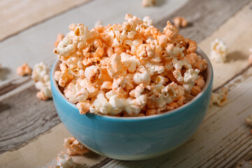 Delicious cheese popcorn in blue bowl in wooden background