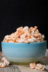 Delicious cheese popcorn in bowl in wooden and black background