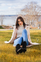 A young girl sits relaxed on a green lawn in a park