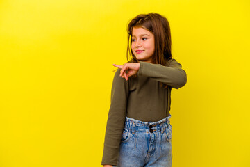 Little caucasian girl isolated on yellow background looks aside smiling, cheerful and pleasant.