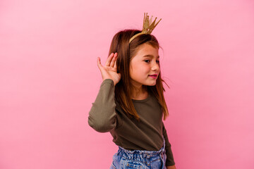 Little princess girl with crown isolated on pink background trying to listening a gossip.