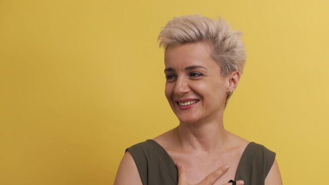 Adult woman on yellow background with blond hair in black medical mask looks directly into camera. Caucasian model is released from mask and sighs with relief. Pandemic stop concept. 