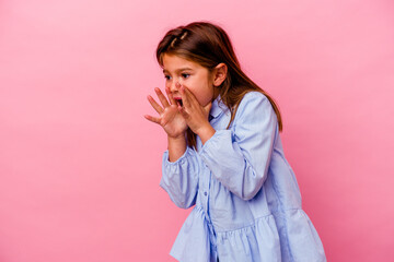 Little caucasian girl isolated on pink background shouts loud, keeps eyes opened and hands tense.