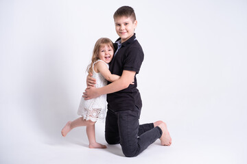 handsome older brother teenager hugging his cute little sister on white background